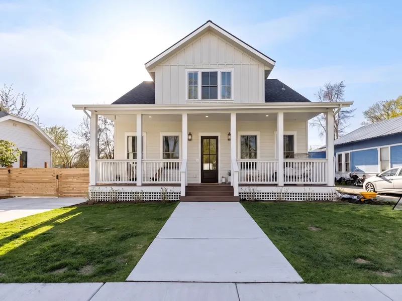 Bright daytime front view of the craftsman home with full wraparound porch and clean landscaping