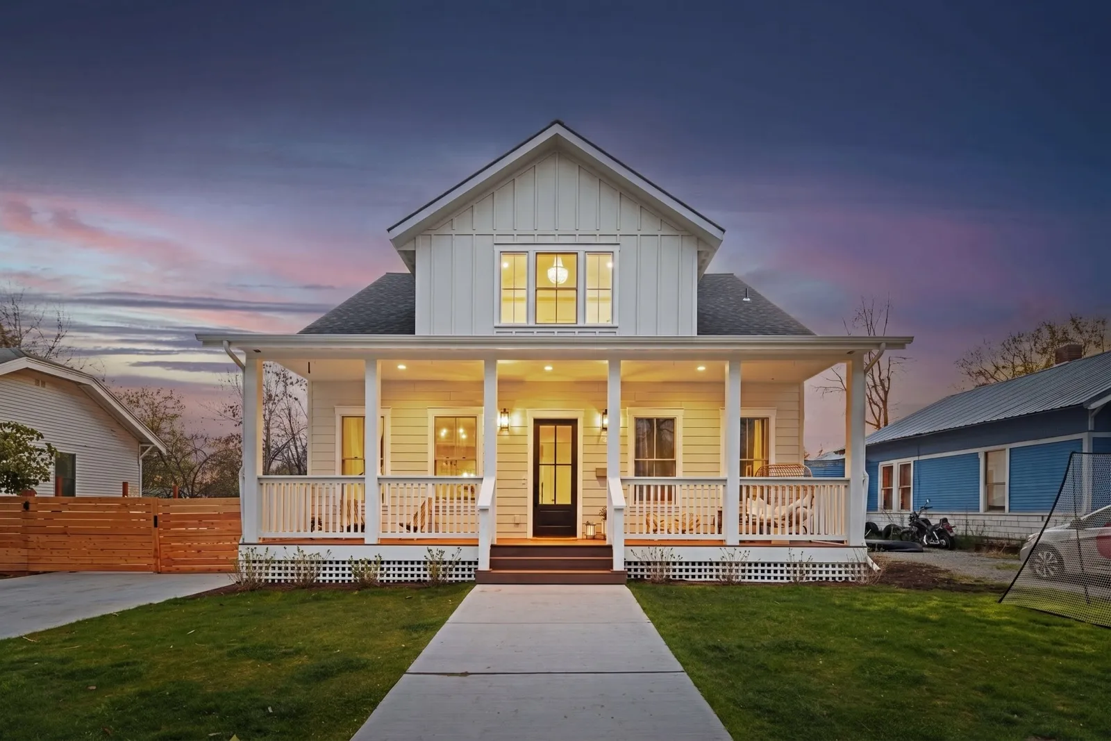 Front view of a craftsman home at dusk with warmly lit windows and porch