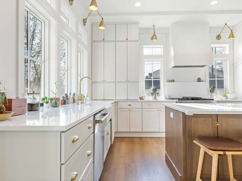 Bright remodeled kitchen with white cabinetry, brass fixtures, and a warm wood island