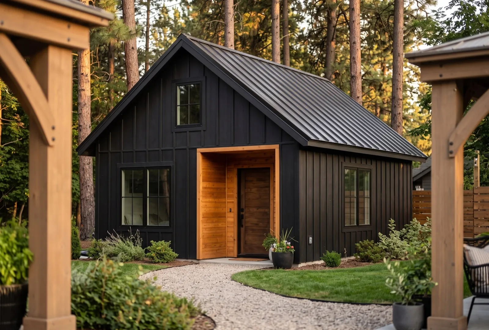 Concept rendering of a small black board-and-batten backyard ADU with a cedar entry among pine trees
