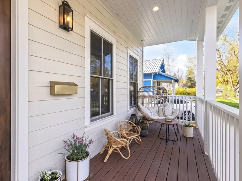 Wraparound front porch seating vignette with rattan furniture