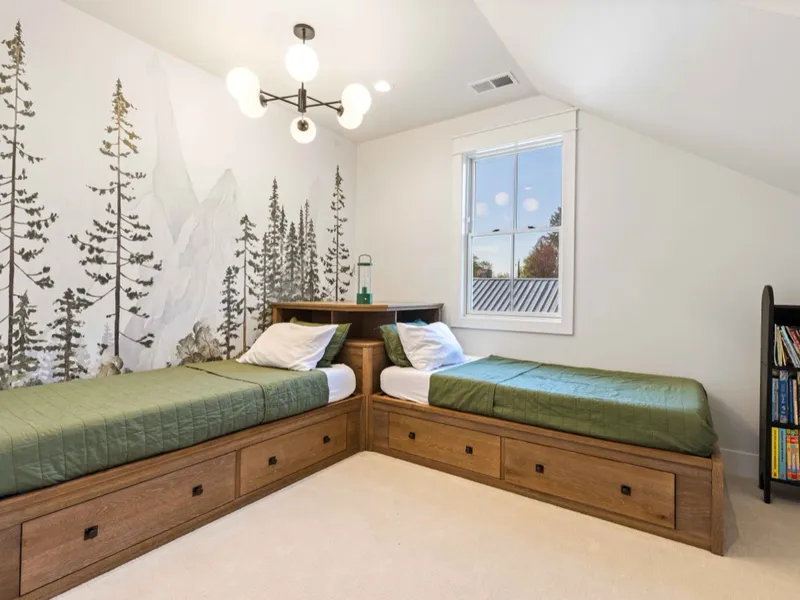 Built-in twin beds with storage drawers and a custom pine-forest mural wall