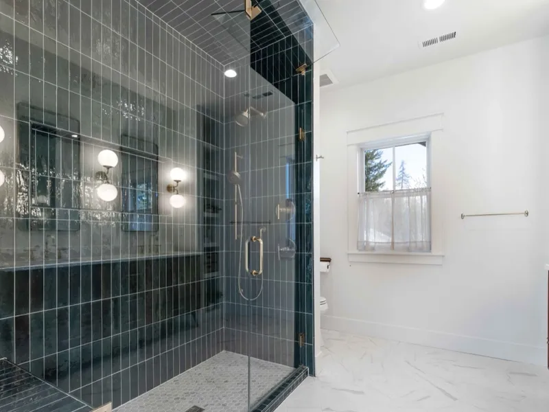 Dark vertical subway tile walk-in steam shower with brass fixtures