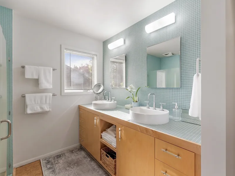 Primary bathroom with a double vanity, blue mosaic tile, and natural light