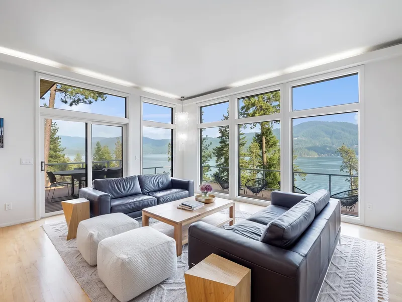 Remodeled Hayden Lake living room with floor-to-ceiling windows overlooking the lake and forested mountains