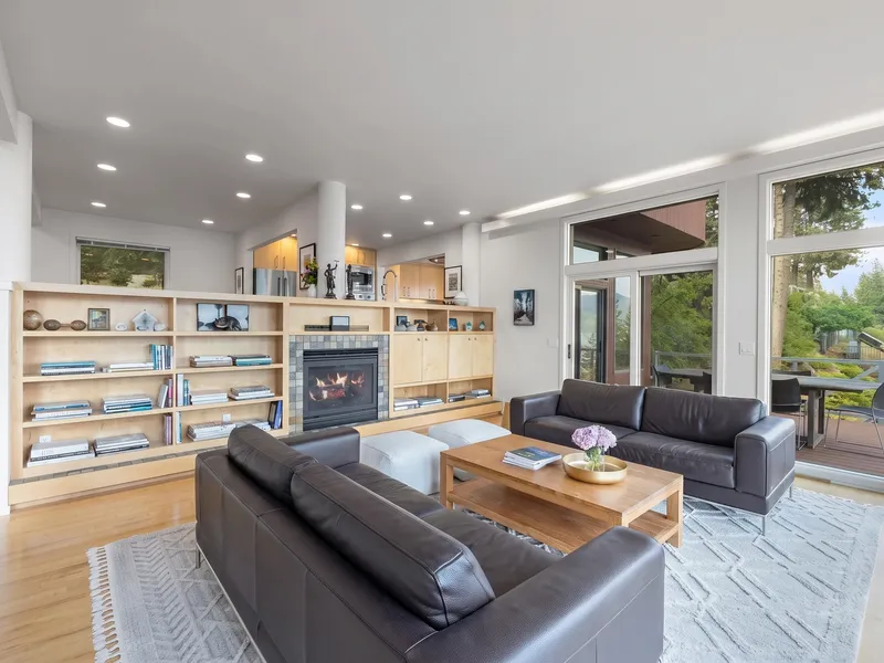 Open living room with a built-in bookshelf, gas fireplace, and glass doors onto a deck overlooking the lake