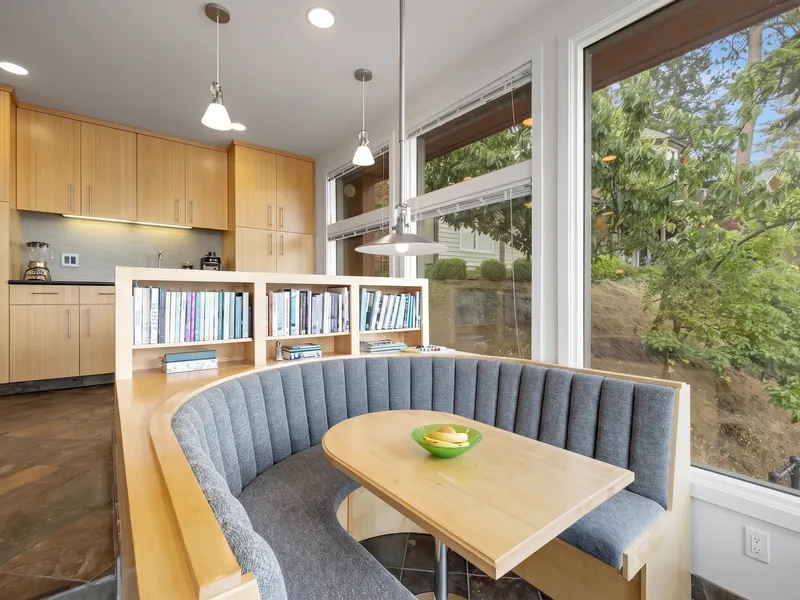 Kitchen and curved built-in breakfast nook with bookshelf and lake and mountain view windows