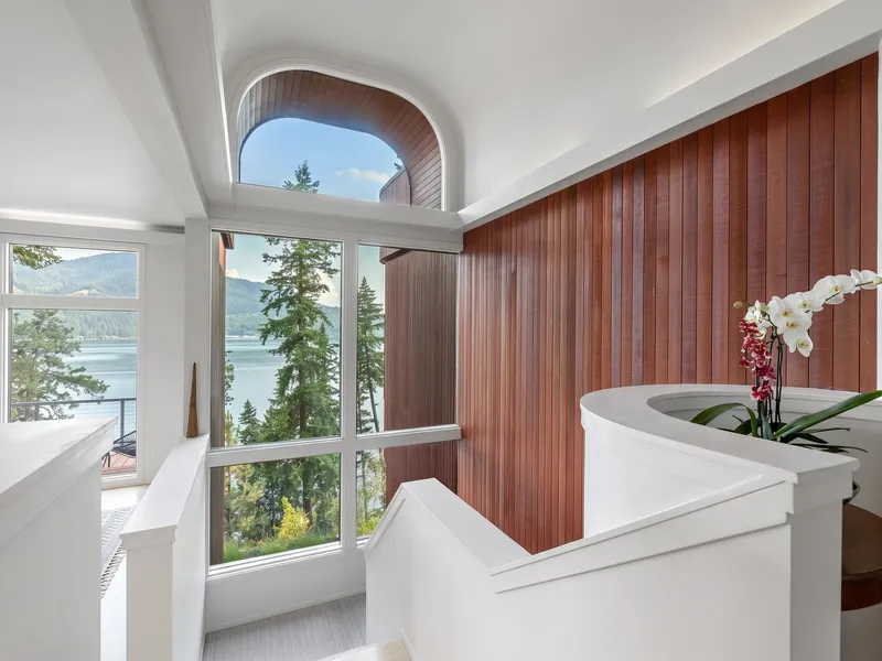 Stairwell with a cedar wood-clad curved wall, arched window nook, and lake view