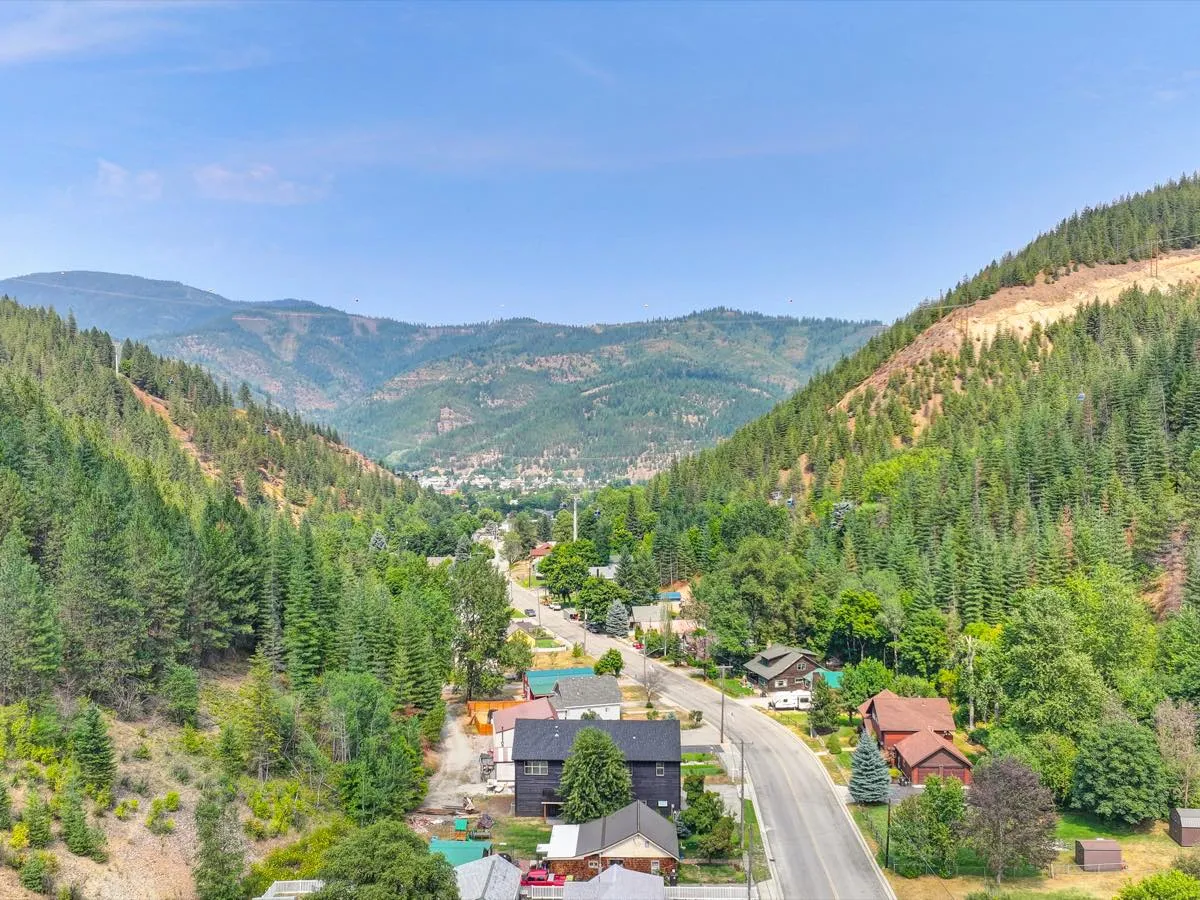 Aerial view of a custom home framed by a forested mountain valley