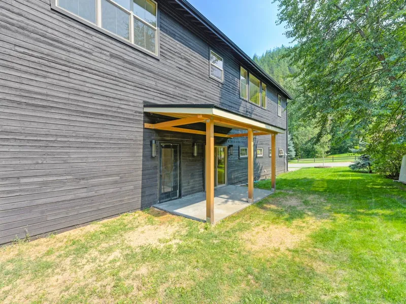 Covered back patio with exposed timber posts and beams overlooking the lawn and forest