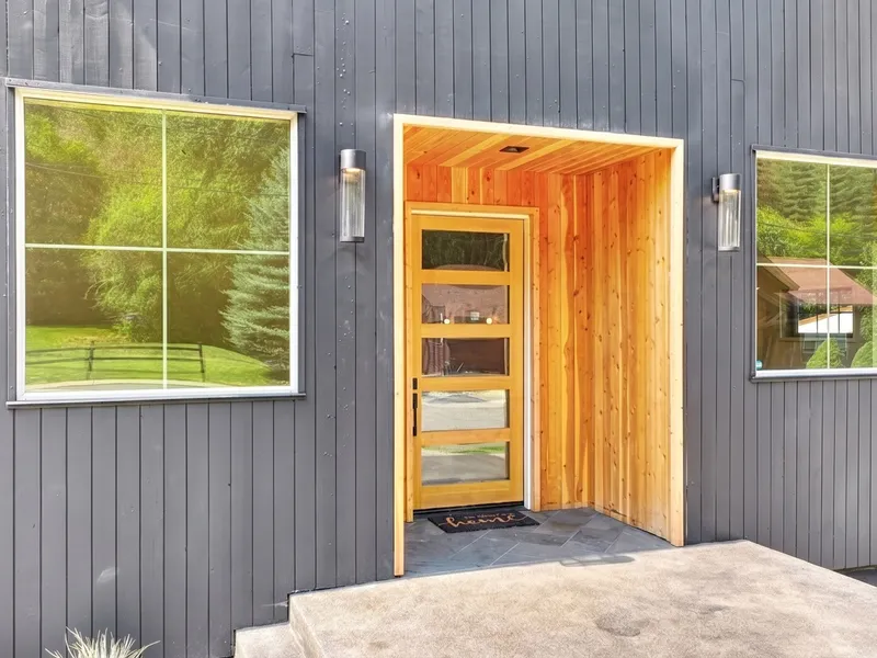 Close-up of the lodge's cedar-clad entry alcove and matching wood door with brass address numerals