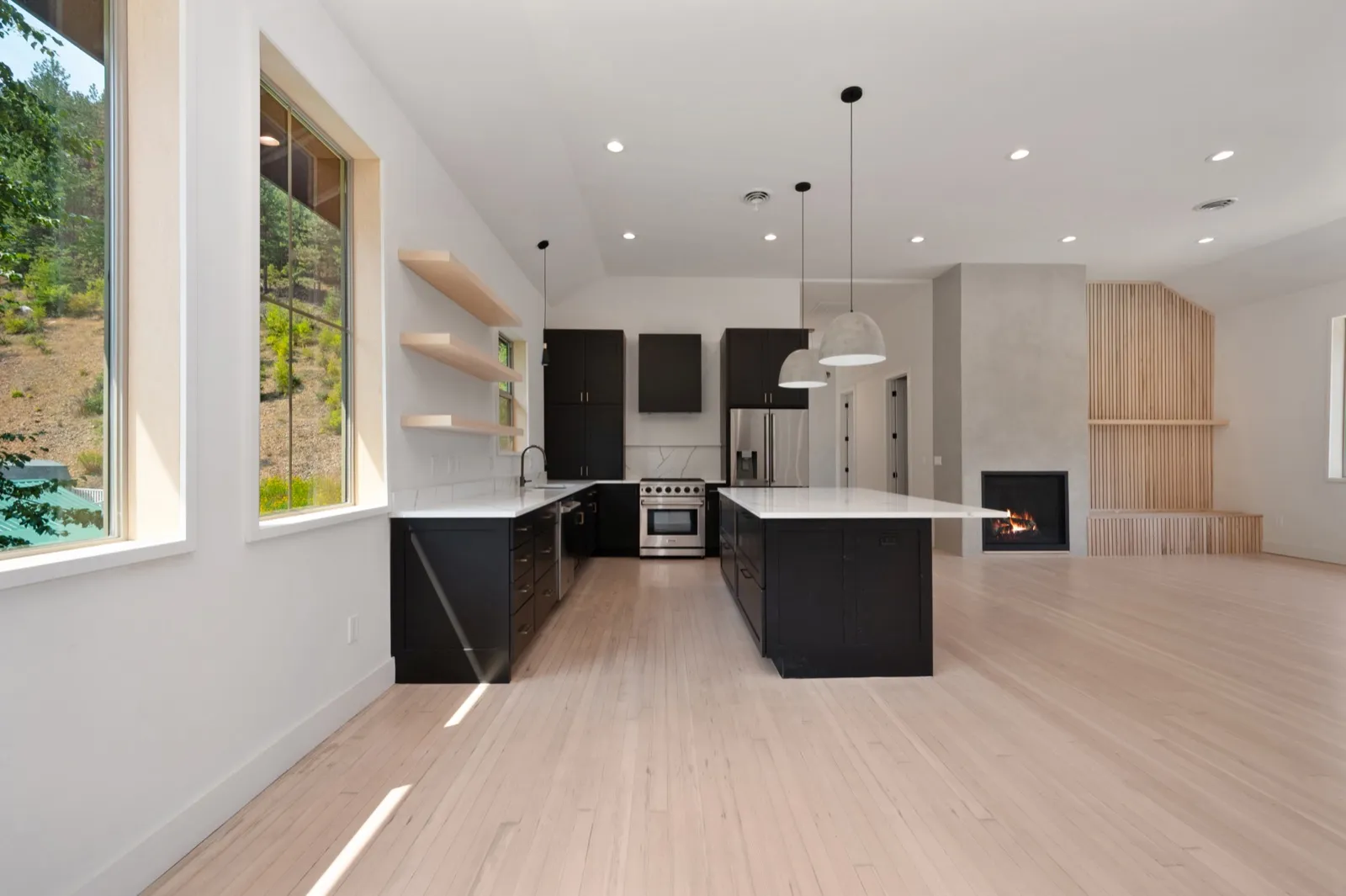 Open-concept kitchen with black shaker cabinetry, a white quartz island, and a lit gas fireplace