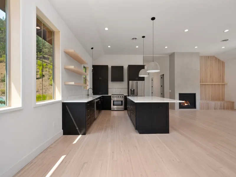 Open-concept kitchen with black shaker cabinetry, a white quartz island, and a lit gas fireplace