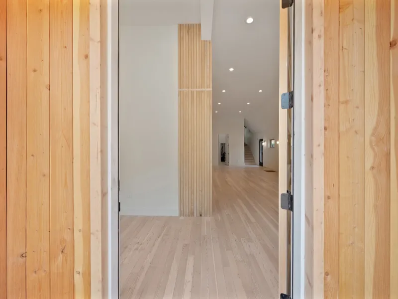 Entry foyer with cedar door slats framing a vertical wood accent wall and white oak flooring