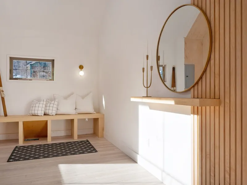 Entry bench nook with a round mirror and vertical wood slat accent wall