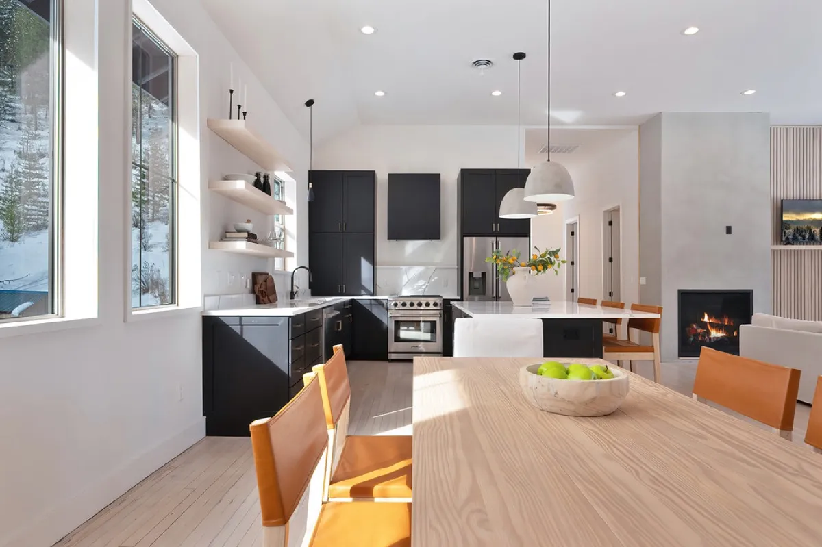 Remodeled kitchen and dining space with black cabinetry, a wood dining table, and a lit fireplace