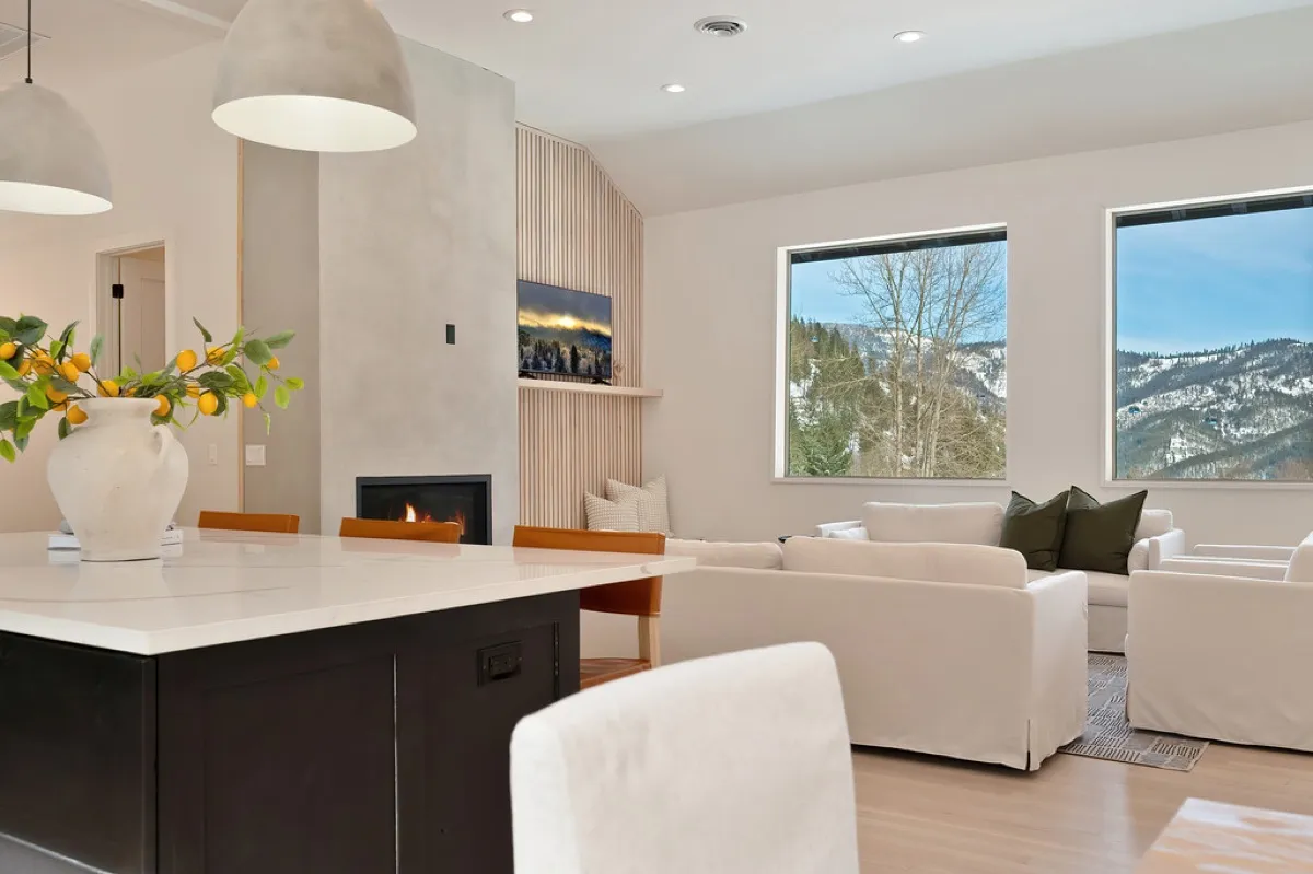 Bright living room with a plaster fireplace, wood slat feature wall, and mountain views through large windows