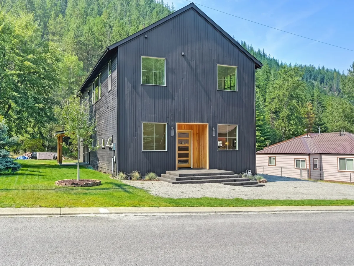 Modern black board-and-batten custom home exterior against a forested hillside